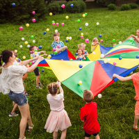 happy-kids-waving-rainbow-parachute-full-balls-green-meadow
